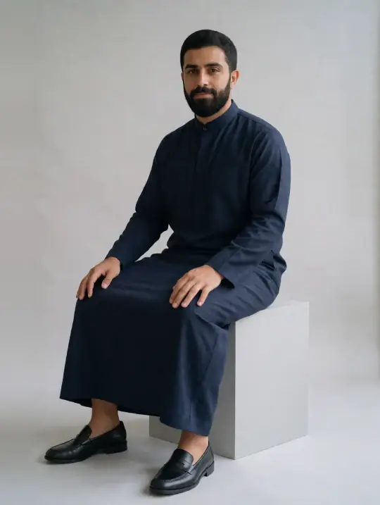 Omar, an Aaina model, in the pose Navy winter thobe, seated at an angle