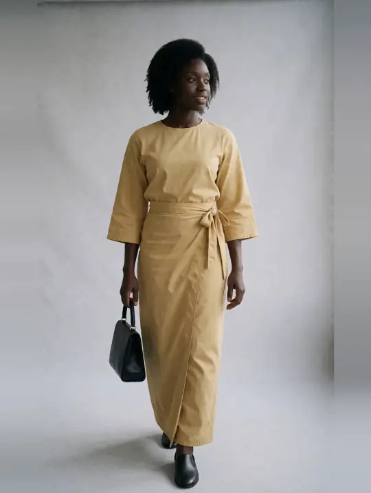 Adaeze, an Aaina model, in the pose Gold wrapper set, walking toward camera, looking away