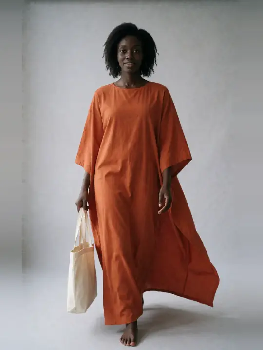 Adaeze, an Aaina model, in the pose Burnt-orange boubou kaftan, walking with tote