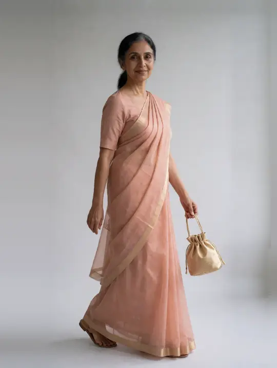 Sunita, an Aaina model, in the pose Peach organza saree, gentle turn toward camera-left