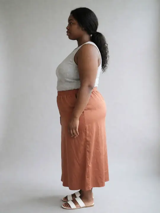 Shanice, an Aaina model, in the pose Grey tank and terracotta maxi skirt, side profile facing camera-left